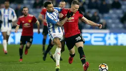 Bek Huddersfield Town, Danny Williams berebut bola dengan pemain Manchester United, Scott McTominay pada pertandingan putaran kelima Piala FA di John Smith's Stadium, Minggu (18/2). MU melaju ke perempatfinal setelah menang 2-0. (Martin Rickett/PA via AP)
