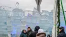 Pengunjung berpose di depan patung es Cristiano Ronaldo di festival Patung Es di Park Pobedy, Poklonnaya Gora, Moskow (4/1). Wajah patung es itu dinilai tak mirip dengan Ronaldo dan menjadi olok-olokan di medsos. (AFP Photo/Mladen Antonov)
