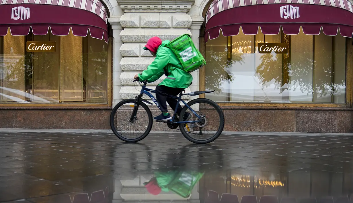 Seorang pengantar makanan mengendarai sepeda di sepanjang department store GUM dengan butik Cartier ditutup karena sanksi barat di Moskow, Rusia, Selasa, 31 Mei 2022. Ketika invasi Rusia ke Ukraina memasuki hari ke-100, kehidupan di Moskow dan St. Petersburg sebagian besar tetap normal, bahkan ketika banyak pengecer Barat mulai hengkang dari negara itu. (AP Photo/Alexander Zemlianichenko)