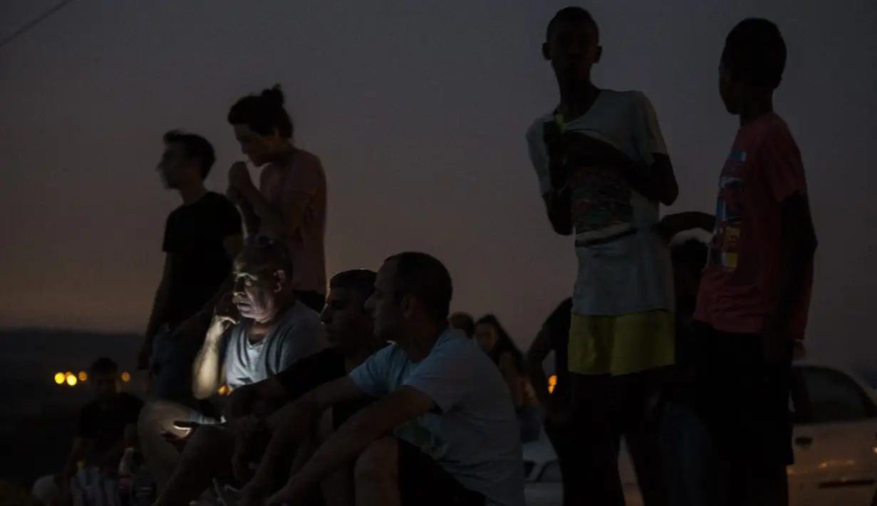 Warga Ibu Kota Tel Aviv ini rela mengemudi hampir 161 kilometer hanya untuk bisa melihat serbuan udara Israel dari jarak dekat. Sudah dua malam berturut-turut di ke bukit itu (AFP Photo/MENAHEM KAHANA)