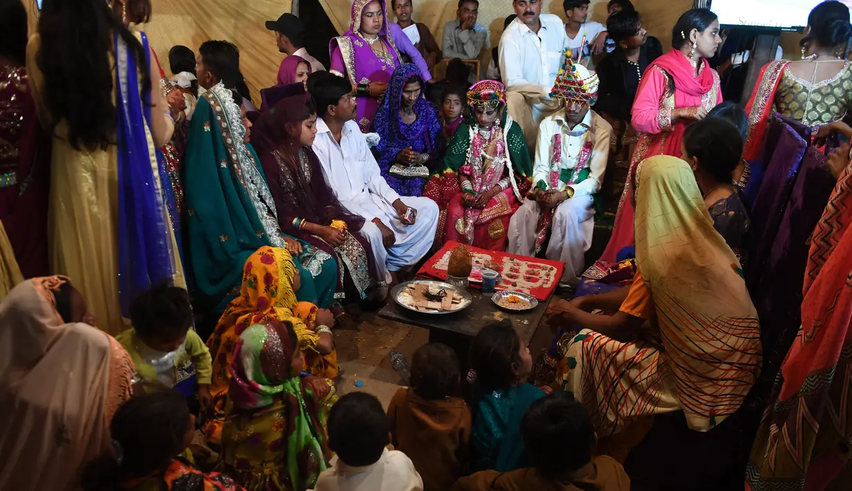 Sejumlah pasangan pengantin menjalani ritual dalam prosesi pernikahan massal umat Hindu di Karachi, Pakistan, (19/3). Sebanyak 62 pasangan pengantin mengikuti pernikahan massal yang merupakan bagian dari perayaan Festival Holi. (AFP Photo /Asif Hassan)