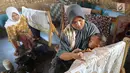 Seorang ibu menyusui anaknya sambil membuat batik tulis di Kampung Batik Puswasedar kawasan Geopark Ciletuh, Sukabumi, Jawa Barat, Sabtu (22/9). Sebelum menekuni pembuatan batik, para perempuan berprofesi sebagai petani. (Merdeka.com/Arie Basuki)