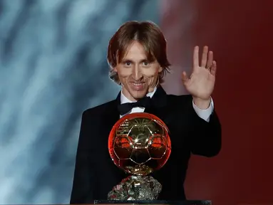 Gelandang Real Madrid, Luka Modric melambaikan tangan sambil memegang penghargaan Ballon d'Or 2018 di Grand Palais, Paris, Senin (3/12). Modric sukses memutus dominasi Cristiano Ronaldo dan Lionel Messi yang bertahan selama satu dekade (AP/Christophe Ena)