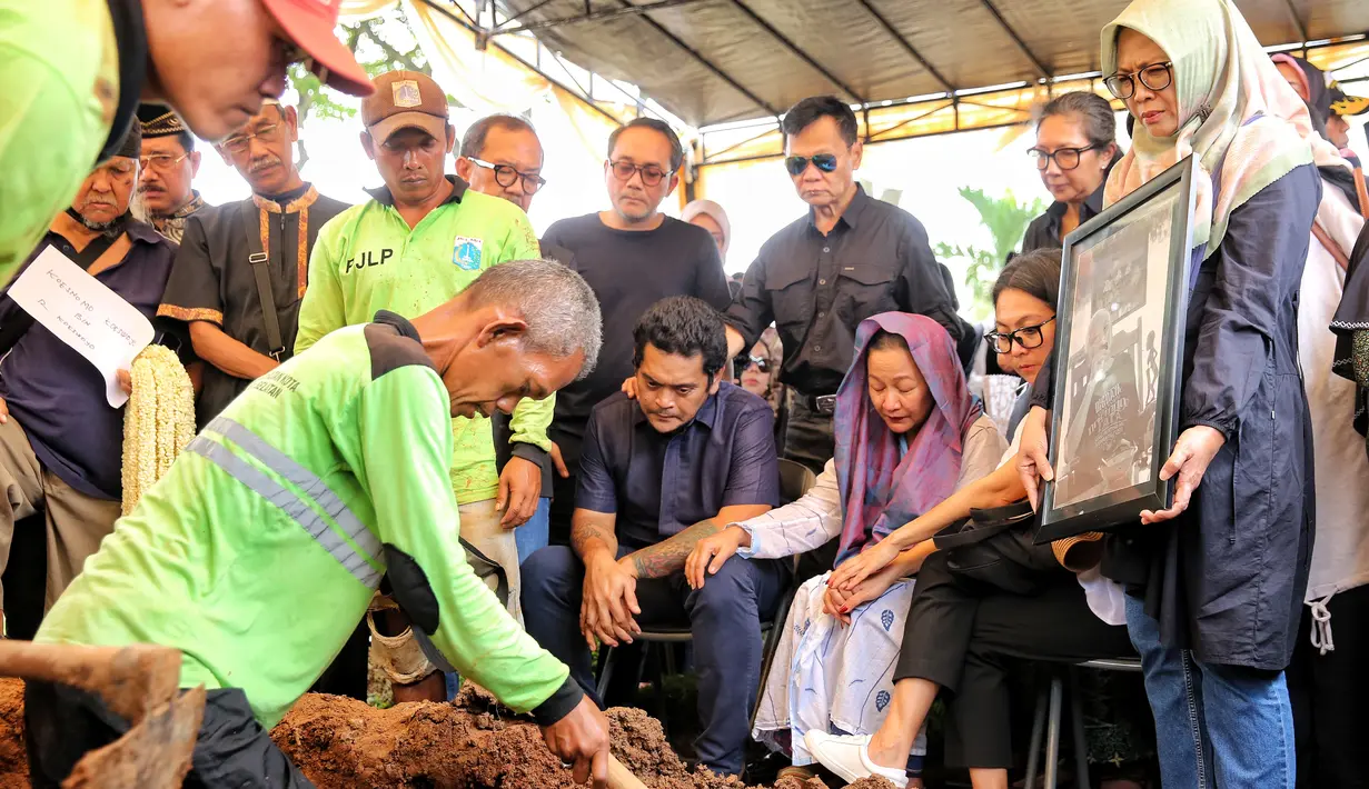 Tangis keluarga pecah saat jenazah personil grup musik legendari Koes Bersaudara dimasukkan ke liang lahat. Tampak beberapa orang juga saling menguatkan. [Foto; Adrian Putra/Fimela.com]