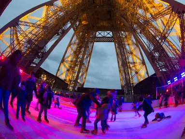 Sejumlah wisatawan menikmati keseruan bermain ice skating di sebuah arena yang dibuka di lantai 1 Menara Eiffel, Paris, 19 Desember 2016. Wahana seluncur es ini memiliki luas sekitar 185 meter persegi di ketinggian 57 meter. (AFP PHOTO/JOEL SAGET)