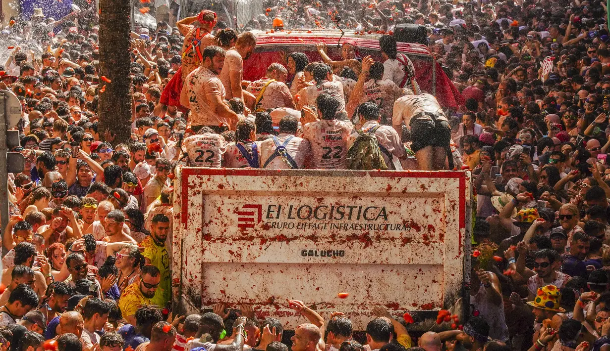 Orang-orang yang bersuka ria saling melempar tomat dalam acara tahunan "Tomatina", pesta pertarungan tomat di desa Bunol dekat Valencia, Spanyol, Rabu (31/8/2022). Pertarungan tomat terjadi sekali lagi setelah penangguhan selama dua tahun karena pandemi virus corona covid-19. (AP Photo/Alberto Saiz)