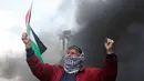 Seorang pria membawa bendera Palestina saat aksi di perbatasan Palestina-Israel, Ramallah, Jumat (17/2). Aksi tersebut untuk memperingati 12 tahun protes mereka atas tembok pemisah tersebut. (AP Photo / Majdi Mohammed)