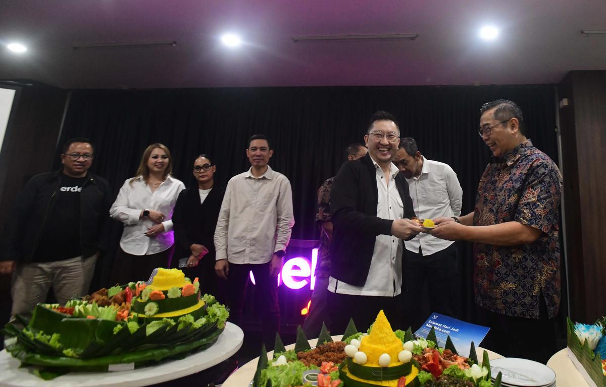 CEO Kapanlagi Universi (KLY) Danny Purnomo (kanan) menyerahkan nasi tumpeng kepada Corporate Secretary SCMA, Gilang Iskandar saat ulang tahun ke 14 Merdeka.com di Gedung KLY, Jakarta, Senin (23/02/2026)