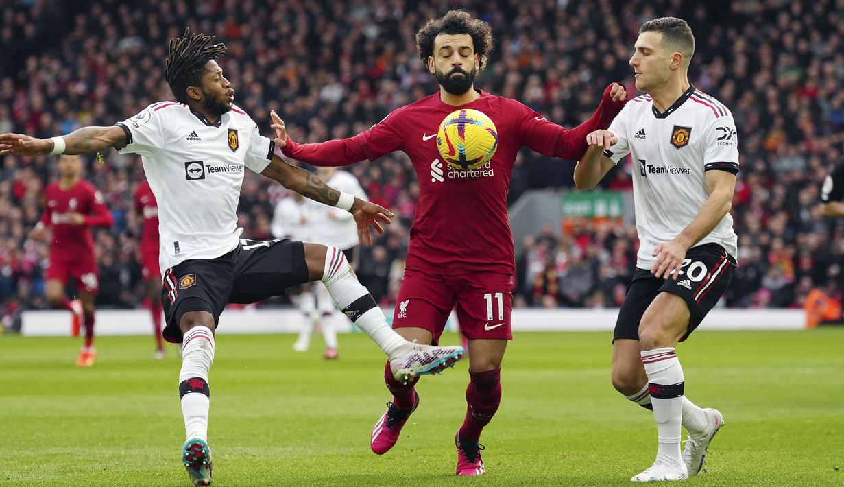 Pemain Liverpool, Mohamed Salah (tengah) berebut bola dengan pemain Manchester United, Fred (kiri) dan Diogo Dalot (kanan) pada laga pekan ke-26 Liga Inggris 2022/2023 yang berlangsung di Anfield, Liverpool, Senin (06/03/2023) WIB. (AP Photo/Jon Super)