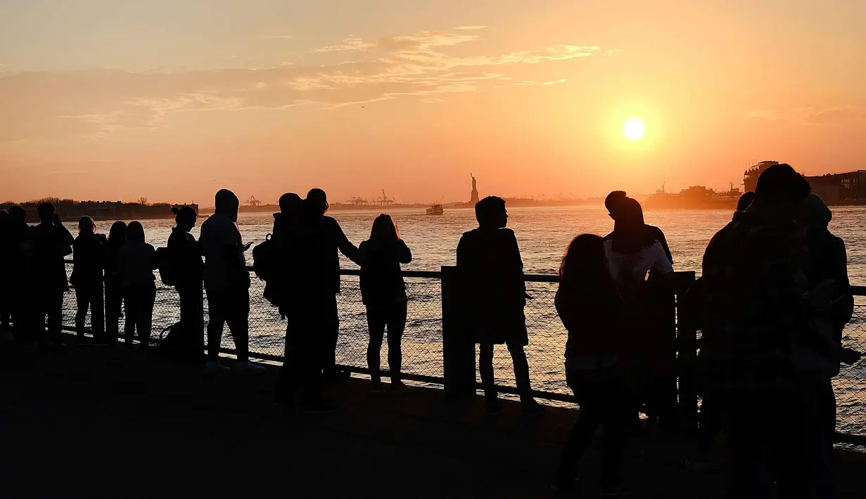 Sejumlah warga menikmati taman Brooklyn saat matahari terbenam di mana suhu mencapai hampir 70 derajat di New York City (21/2). Cuaca New York akan berubah kembali ke musim dingin dengan suhu yang diperkirakan 30 derajat. (AFP Photo/Spencer Platt)