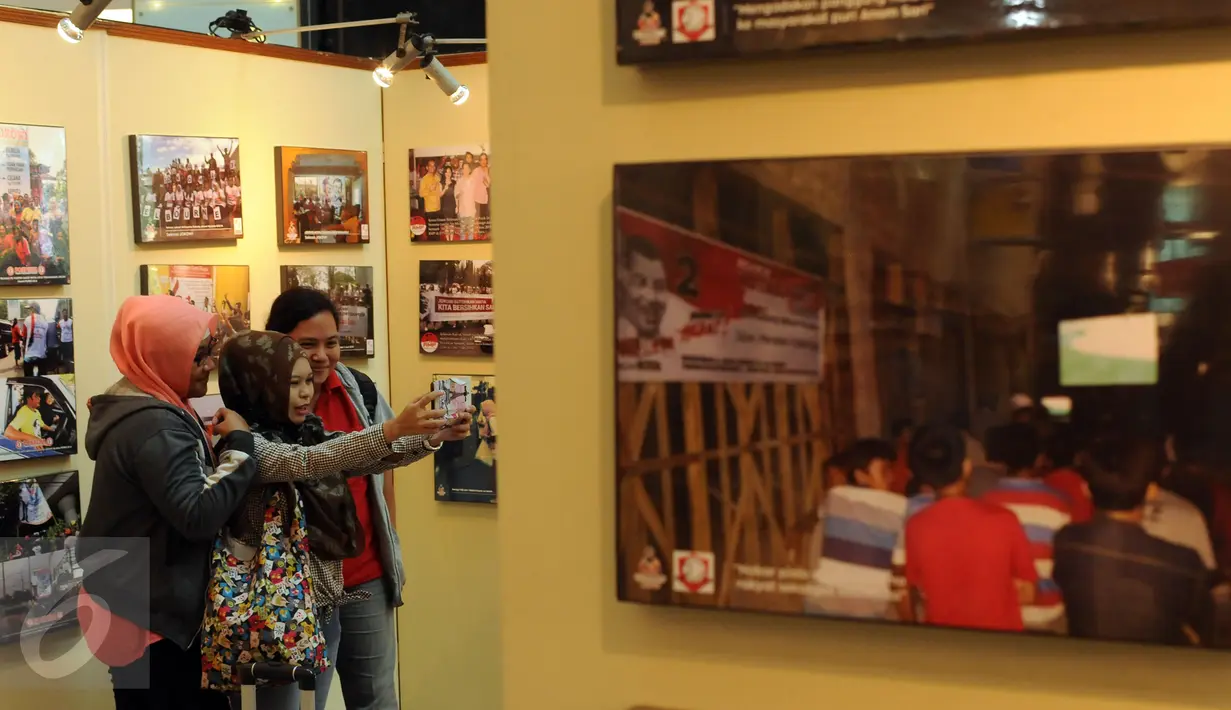 Pengunjung berfoto di antara koleksi foto relawan Jokowi yang dipamerkan di Plaza Atrium Senen, Jakarta, Sabtu (23/4/2016). Hingga 29 April mendatang, Relawan Jokowi menggelar pameran foto dukungan dan diskusi. (Liputan6.com/Helmi Fithriansyah)