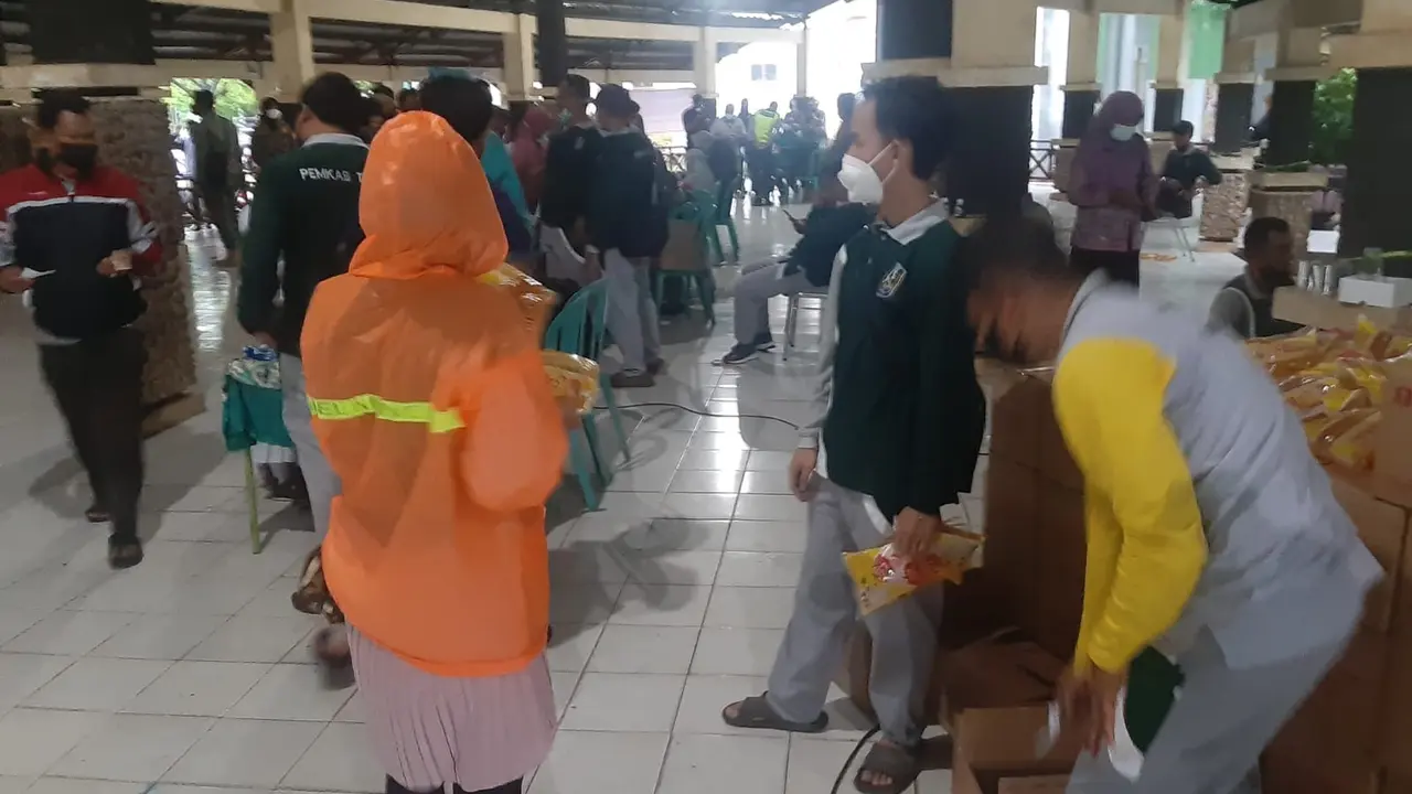 Dengan mengenakan mantel hujan, emak-emak di Tuban antre membeli minyak goreng. (Ahmad Adirin/Liputan6.com)