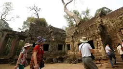 Wisatawan mengunjungi kompleks kuil Ta Prohm di provinsi Siem Reap, Kamboja. Dengan membiarkan lilitan akar pohon besar memeluk tubuh candi inilah keunikan yang menjadikan Ta Phrom salah satu candi paling banyak dikunjungi wisatawan. (REUTERS/Samrang Pring)