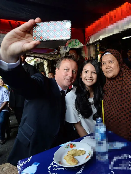 Dalam kunjungannya, David Cameron ditemani penyanyi cantik Maudy Ayunda. Mereka melakukan foto selfie bersama ibu pemilik warung. (via dailymail.co.uk)
