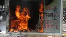 Mesin ATM bitcoin bernama Chivo terbakar selama protes terhadap kebijakan Presiden Nayib Bukele pada Hari Kemerdekaan di San Salvador, El Salvador, Rabu (15/9/2021). Ribuan warga Salvador berdemonstrasi menentang bitcoin, yang disahkan sebagai alat pembayaran oleh pemerintah. (MARVIN RECINOS/AFP)