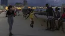 Seorang gadis bermain lompat tali sementara orang lain menghabiskan sore hari di Malecon di Havana, Kuba, pada Rabu (29/9/2021). Pihak berwenang di Kuba mulai melonggarkan pembatasan COVID-19 di beberapa kota seperti Havana dan Varadero. (AP Photo/Ramon Espinosa)