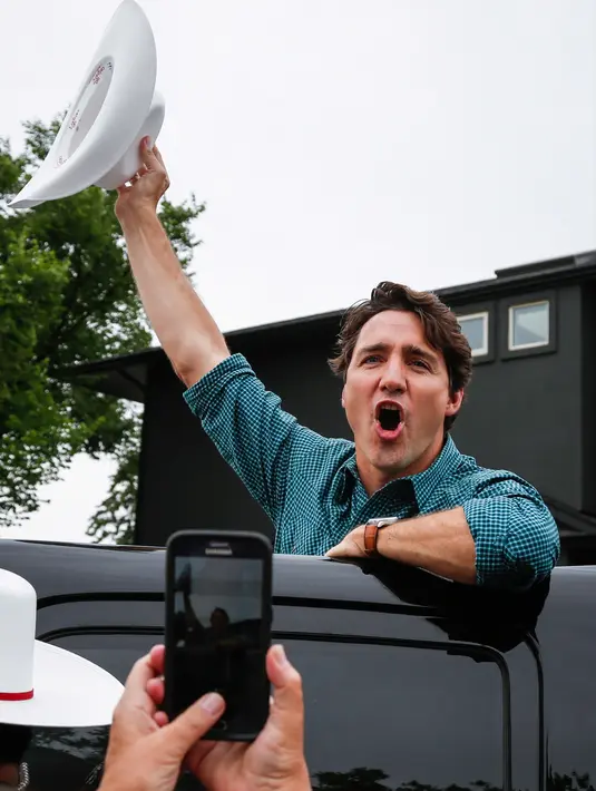 Perdana Menteri Kanada Justin Trudeau mengangkat topi koboinya saat menyapa warga saat acara Calgary Stampede di Calgary, Alberta, Kanada (15/7). (Jeff McIntosh / The Canadian Press via AP)