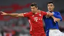 Penyerang Bayern Munchen, Robert Lewandowski, berebut bola dengan bek Schalke, Ozan Kabak, pada laga Liga Jerman di Allianz Arena, Sabtu (19/9/2020) dini hari WIB. Bayern Munchen menang 8-0 atas Schalke. (AFP/Christof Stache)