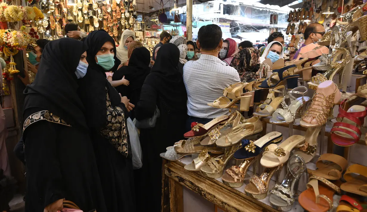 Sejumlah wanita mencari sandal saat berbelanja di sebuah pasar di Lahore, Pakistan (4/5/2021). Di tengah pandemi virus corona Covid-19, sejumlah warga memadati area pasar tersebut menjelang hari Idul Fitri. (AFP/Arif Ali)