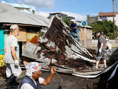 Warga memperbaiki atap yang rusak akibat angin kencang menyusul topan Haishen di Amami, prefektur Kagoshima, barat daya Jepang, Senin (7/9/2020). Topan kuat kedua yang melanda wilayah tersebut dalam sepekan ini menyebabkan sejumlah orang terluka dan banyak bangunan rusak. (Kyodo News via AP)