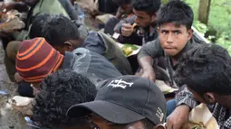 Sejumlah warga Rohingyah menikmati makanan di sbuah pos Lanal Kuala Idi, Aceh Timur (4/12). Menurut pihak berwenang, para pengungsi Rohingya mendarat ke perairan Idi dengan menggunakan perahu tepat pukul 08.00 WIB. (AFP Photo/Cek Mad)