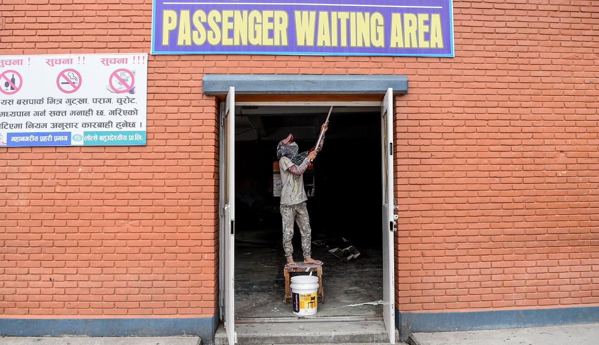 Seorang pekerja mengecat di ruang tunggu penumpang di terminal bus di Kathmandu, Kamis (17/9/2020). Pemerintah Nepal melonggarkan pembatasan yang diberlakukan sebagai tindakan pencegahan virus corona pada transportasi umum jarak jauh. (PRAKASH MATHEMA/AFP)