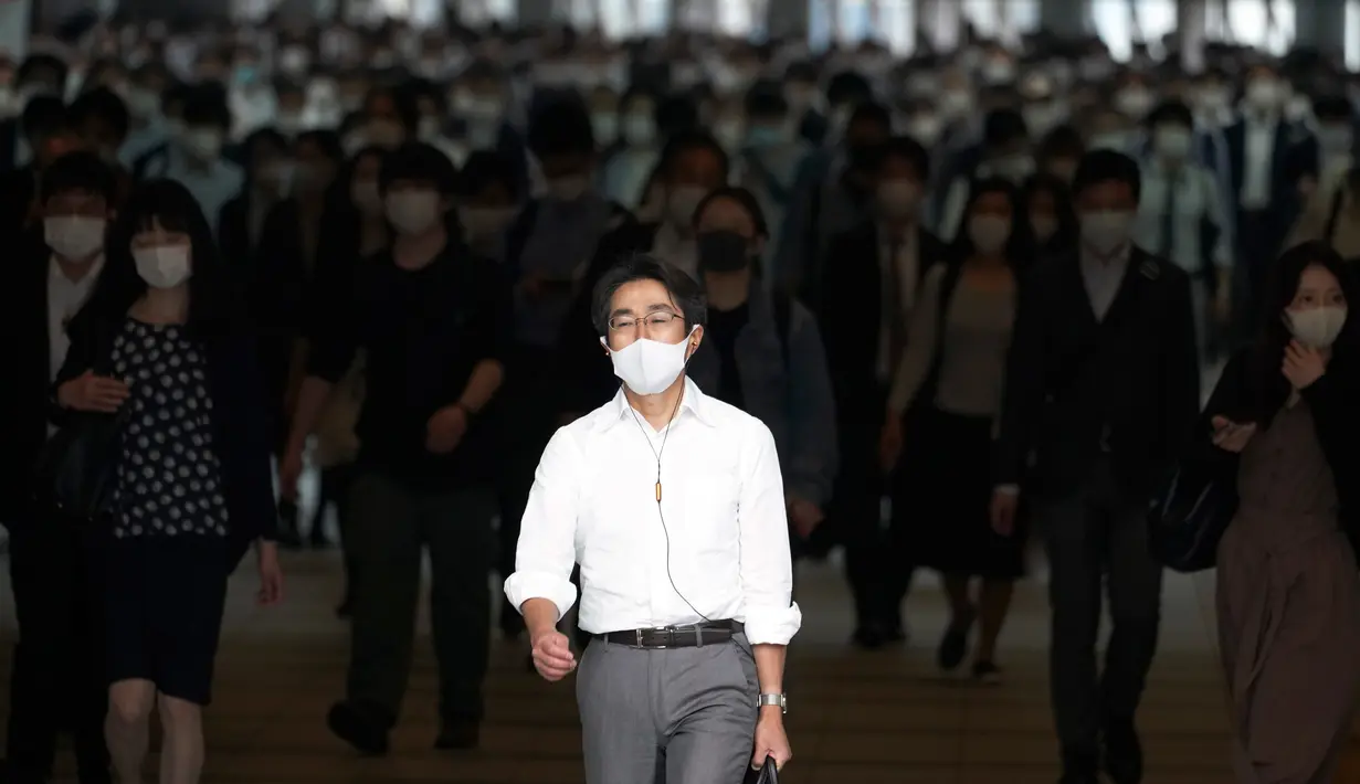 Para penumpang dengan menggunakan masker memenuhi sebuah lorong stasiun selama jam sibuk di Tokyo, Selasa (26/5/2020). Perdana Menteri Jepang Shinzo Abe mencabut keadaan darurat pandemi virus corona di Tokyo dan empat wilayah lainnya pada Senin (25/5). (AP Photo/Eugene Hoshiko)