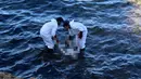 Petugas mengangkat mayat yang terapung di pantai di Kota Pesisir Tajoura, Libya, Minggu (4/12). Diduga orang yang tenggelam itu akan meninggalkan Libya karena berharap dapat menjadi imigran di negara lain. (REUTERS / Hani Amara)