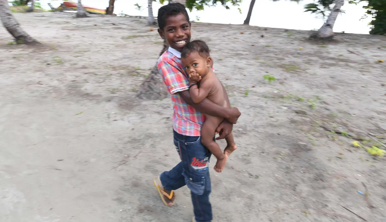 Anak laki-laki suku Byak Betew membawa adiknya dalam perjalanan ke gereja untuk misa hari Minggu di pulau Saukabu, satu dari 1.500 pulau di Raja Ampat 20 Agustus 2017. (AFP Photo/Goh Chai Hin)
