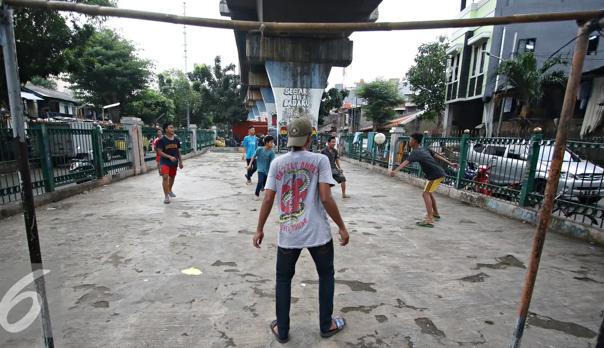 Sejumlah remaja bermain sepak bola di kolong rel kereta kawasan Juanda, Jakarta, Jumat (27/5). Tidak tersedianya ruang terbuka menyebabkan lahan tersebut dijadikan tempat bersosialisasi bagi warga. (Liputan6.com/Immanuel Antonius)