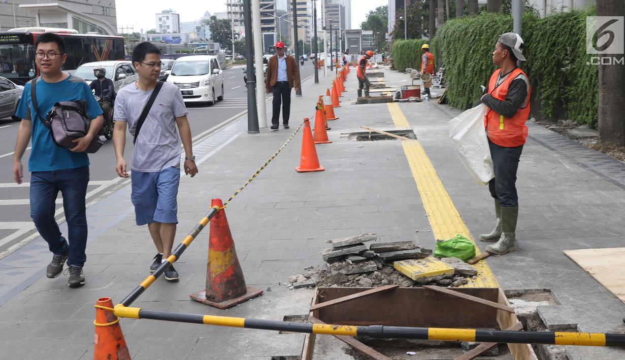 Pejalan kaki melihat peremajaan gorong-gorong di kawasan Thamrin, Jakarta, Selasa (15/1).Peremajaan dilakukan untuk mengantisipasi terjadinya penyumbatan saluran yang dapat menyebabkan banjir di kawasan tersebut. (Liputan6.com/Angga Yuniar)