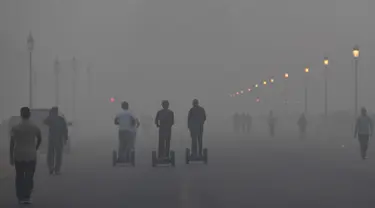 Pejalan kaki menyusuri jalan di tengah kondisi kabut asap tebal di New Delhi (2/11). Tingkat kabut melonjak selama musim dingin di Delhi, ketika kualitas udara melampaui tingkat aman Organisasi Kesehatan Dunia. (AP Photo/Money Sharma)