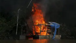 Sebuah kapak tambang dibakar selama operasi terhadap penambangan emas ilegal di perairan hutan hujan Amazon, Roraima, Brasil (16/4). Meski telah dilarang, masih banyak penambang liar yang menjadikan tempat ini tercemar. (REUTERS / Bruno Kelly)