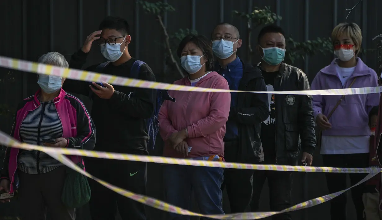 Warga berbaris di belakang pita peringatan untuk mendapatkan swab tenggorokan COVID-19 rutin mereka di tempat pengujian virus corona di Beijing, Kamis (6/10/2022). Xinjiang yang luas adalah wilayah China terbaru yang terkena pembatasan perjalanan COVID-19, karena China semakin meningkatkan langkah-langkah pengendalian menjelang kongres penting Partai Komunis akhir bulan ini. (AP Photo/Andy Wong)