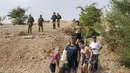 Tentara Israel berjaga-jaga saat warganya asyik bermain air di sebuah kanal kecil di Desa Al-Auja selama perayaan keagamaan Yahudi dalam Festival Sukkot di Tepi Barat (17/10/2019). (AFP Photo/Menahem Kahana)