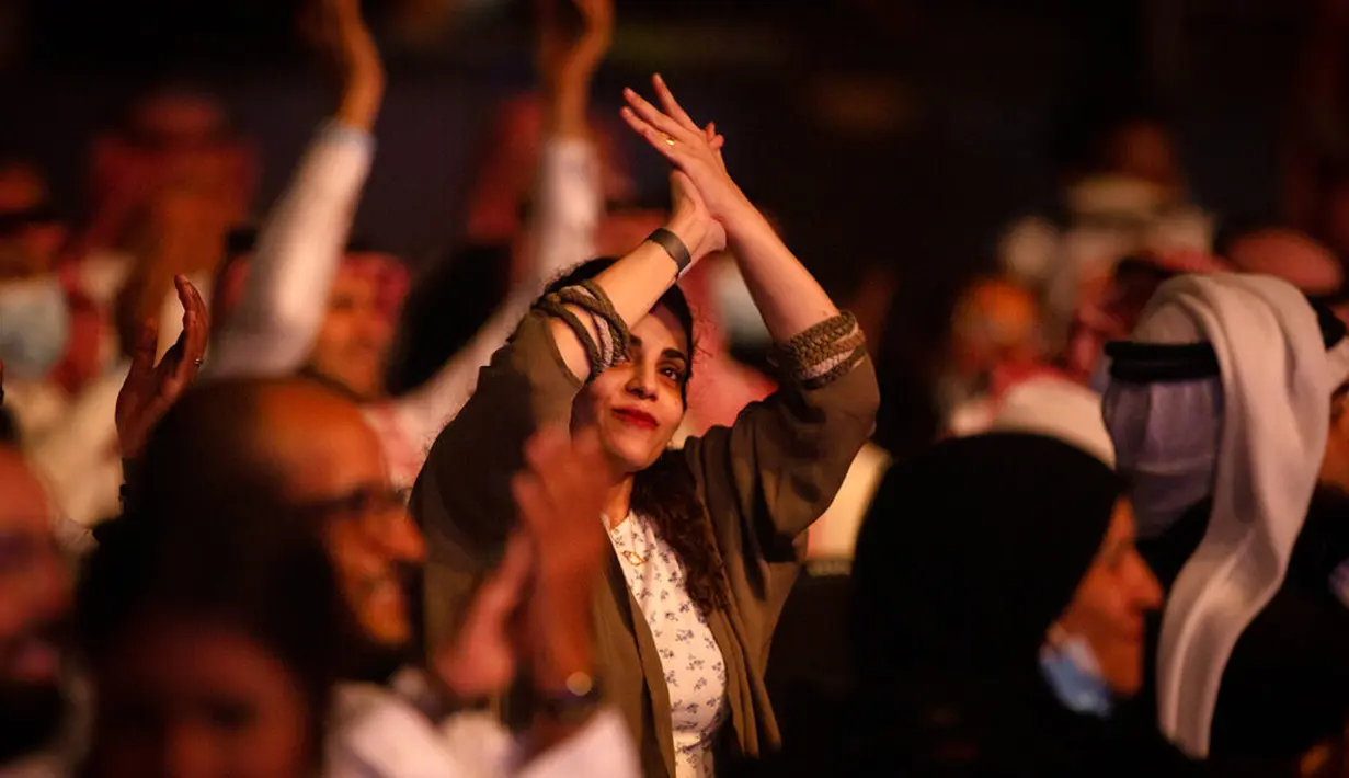 Seorang wanita yang telah divaksinasi virus corona bertepuk tangan saat menonton penyanyi Saudi Mohammed Abdu di Super Dome di Jeddah, Arab Saudi (8/7/2021). Konser ini diselenggarakan Otoritas Hiburan Umum Saudi. (AP Photo/Amr Nabil)