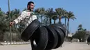 Mohamed Barka, pria yang dijuluki "Super Hero" asal Palestina saat berusaha mengangkat sejumlah ban menggunakan gigi dalam aksinya di Deir Al-Balah, Gaza Tengah, Kamis (4/2). (MOHAMMED ABED/AFP)
