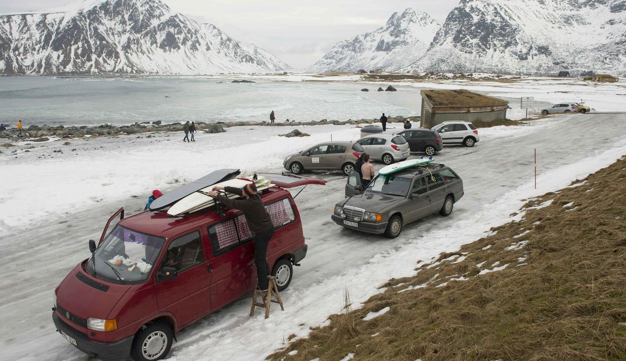 Para peselancar mempersiapkan peralatan saat tiba di kawasan pantai  Flackstad, dekat Ramberg, kepulauan Lofoten, Arctic Circle, (10/3/2016). suhu laut berkisar 5-65-6 ∞C sedangkan suhu udara   0∞C.  (AFP/Olivier Morin)