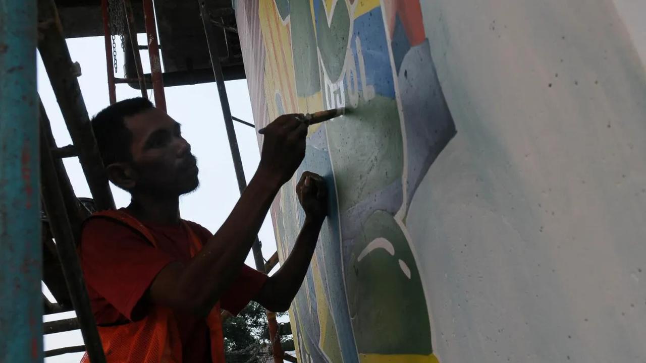 Pegiat seni lukis Jakarta Mural menyelesaikan pembuatan mural BPJS Ketenagakerjaan (BPJAMSOSTEK) yang menghiasi Kolong Tol Becakayu di Jakarta, Kamis (12/10/2023).