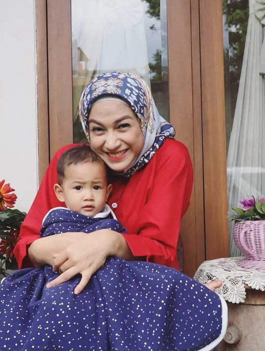 Saat bermain dengan buah hatinya, Kenzie Naratama Chandra, style berhijab Nina membuatnya sangat cantik.  Wajahnya semakin merona, apalagi dengan hijab bermotifnya yang dipadukan dengan blus berwarna merah. (Instagram/ninazatulini22)