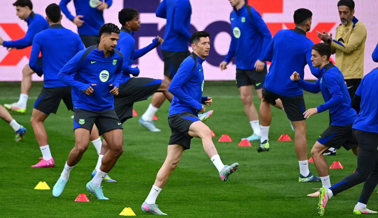 Penyerang Barcelona asal Polandia, Robert Lewandowski (tengah) melakukan pemanasan bersama rekan-rekan setimnya saat sesi latihan di Stadion Signal Iduna Park, Dortmund, Jerman pada 14 April 2025. (Ina FASSBENDER/AFP)