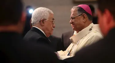 Presiden Palestina Mahmoud Abbas (kiri) berjabat tangan dengan pendeta saat menghadiri misa Natal di Gereja Nativity, Bethlehem, Jumat ( 25/12/2015). Presiden Abbas berharap cita-citanya mewujudkan perdamaian di Palestina bisa. (REUTERS /Fadi Arouri )