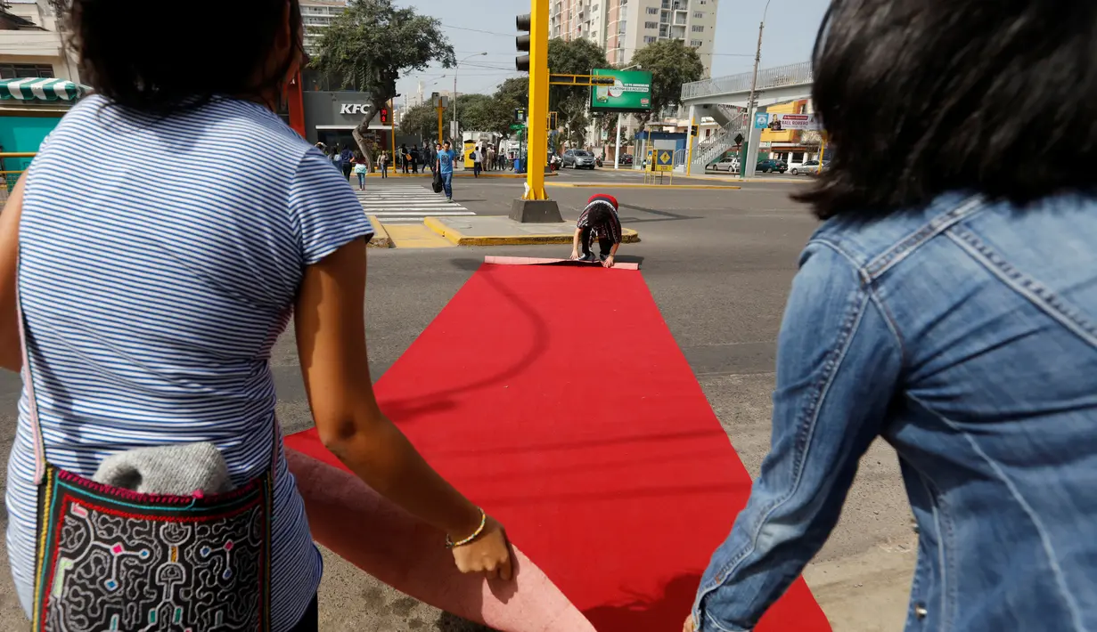 Warga membentangkan karpet merah di salah satu ruas jalan di distrik Magdalena del Mar, Lima, Peru, (2/7). Warga melakukan ini untuk menggugah kesadaran warga perkotaan agar bisa menghormati pejalan kaki. (REUTERS / Guadalupe Pardo)
