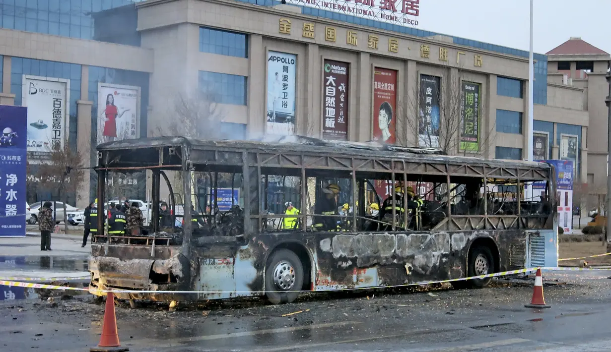 Petugas pemadam kebakaran saat memeriksa isi dalam bus usai hangus terbakar di sebuah jalan di Yinchuan, China, (5/1). 14 orang tewas dan 30 lainnya terluka akibat peristiwa ini. (REUTERS / Stringer)