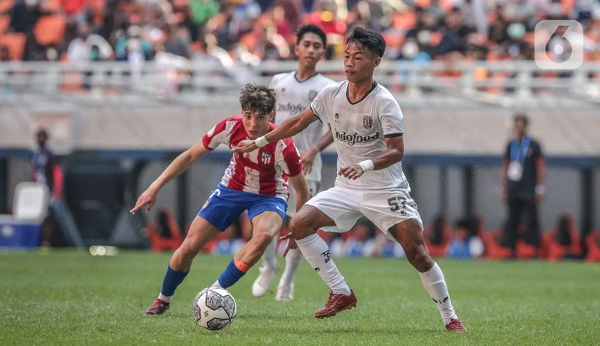 Pemain Bali United U-18 I Kadek Ari Premana berebut bola dengan pemain Atletico Madrid U-18 pada laga perdana International Youth Championship (IYC) 2021 di Jakarta International Stadium (JIS), Jakarta, Rabu (13/4/2022). Atletico Madrid U-18 menang dengan skor 5-0. (Liputan6.com/Faizal Fanani)