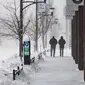 Orang-orang berjalan saat terjadi badai salju di lingkungan East Village, Des Moines, Iowa, pada tanggal 12 Januari 2024. (Christian MONTERROSA/AFP)