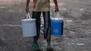 Seorang gadis membawa ember berisi air yang dikumpulkan dari truk tangki air perusahaan kota di lingkungan berpenghasilan rendah di New Delhi pada Kamis (3/6/2021). Kelangkaan air secara tidak proporsional mempengaruhi orang-orang rentan di masyarakat berpenghasilan rendah. (Money SHARMA / AFP)