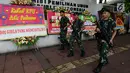 Sejumlah tentara bersenjata berjalan melintasi karangan bunga yang ada di Gedung Komisi Pemilihan Umum (KPU), Jakarta, Sabtu (20/4). Karangan bunga terus berdatangan ke Gedung KPU. (merdeka.com/Imam Buhori)