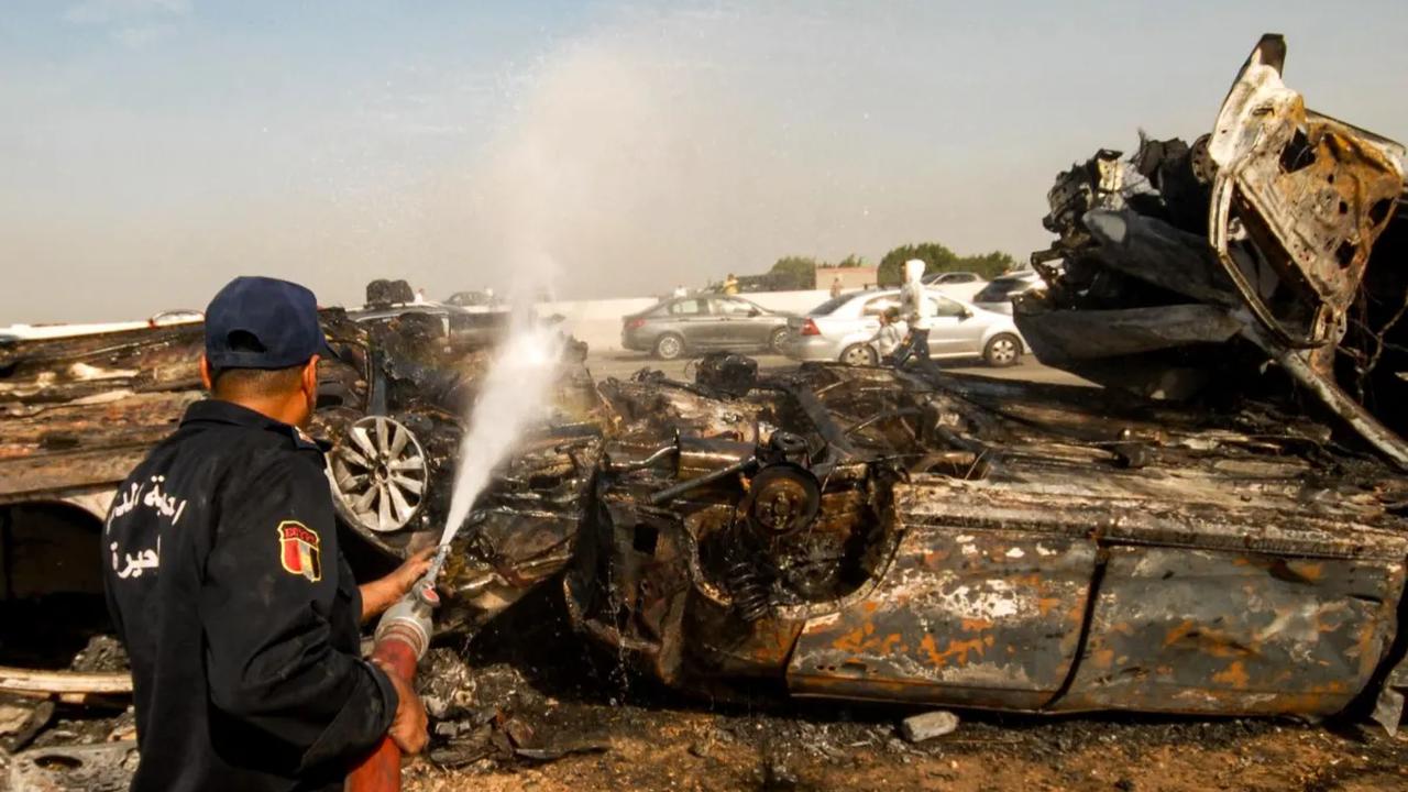Anggota pertahanan sipil Mesir melakukan pendinginan pada kendaraan yang hangus terbakar di lokasi tabrakan beruntun yang melibatkan puluhan kendaraan di sepanjang jalan raya gurun Kairo-Alexandria pada 28 Oktober 2023. <br>