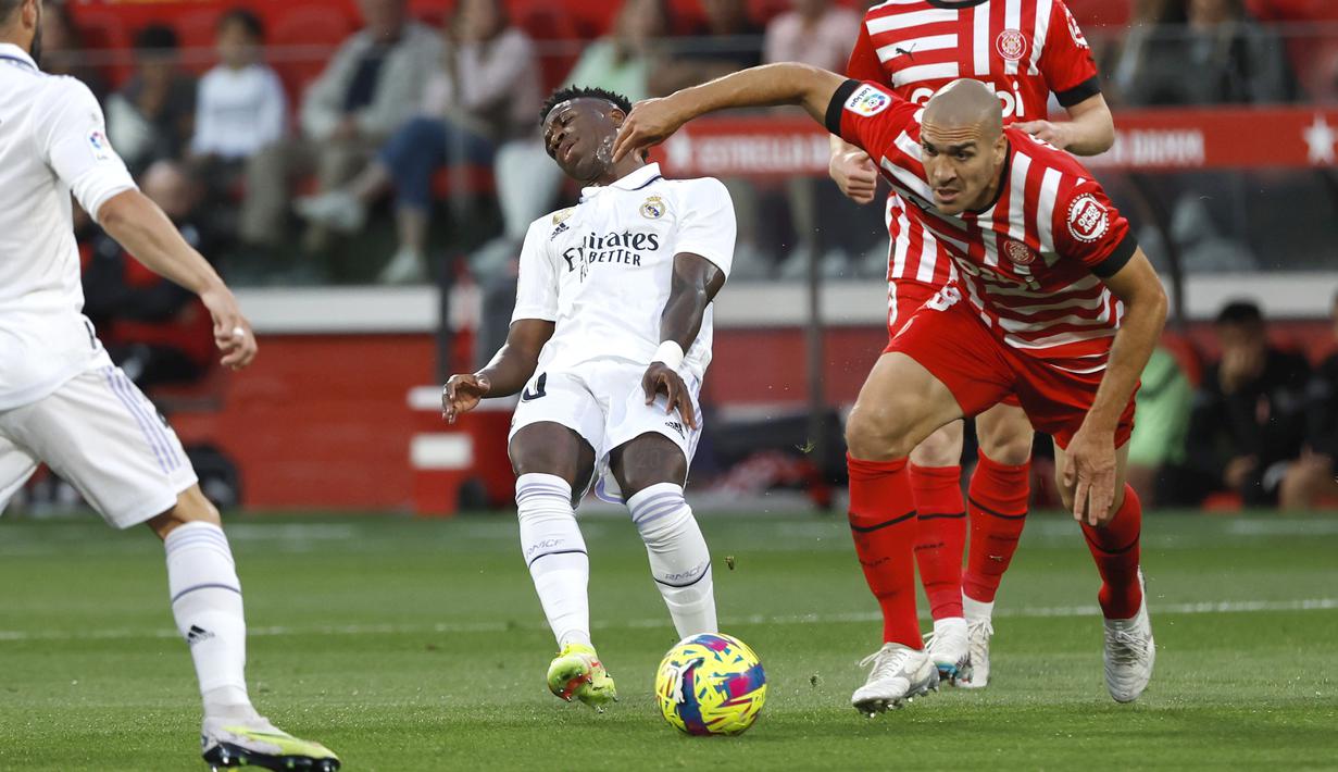 Pemain Real Madrid, Vinicius Junior, terjatuh saat berebut bola dengan pemain Girona, Oriol Romeu, pada laga Liga Spanyol di Stadion Montilivi, Rabu (26/04/2023). Los Blancos dipecundangi tetangga Barcelona itu dengan skor 2-4. (AP Photo/Joan Monfort)